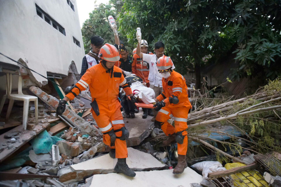 Emergency service workers carrying person out of rubble on stretcher