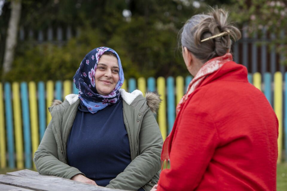 Woman refugee, Yanal, smiling speaking to another woman
