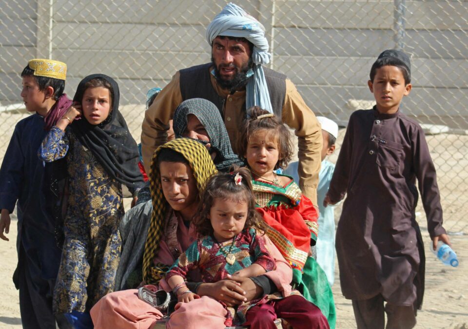 Afghan family of 8 walking with belongings looking distressed