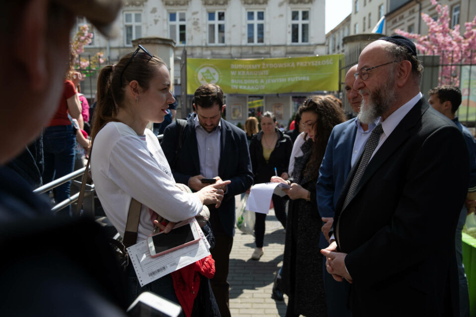 Chief Rabbi Ephraim Mirvis speaking to woman outside building