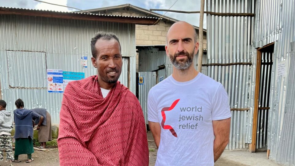 Man, Tilahun, Standing next to World Jewish Relief Team member Kai Hopkins