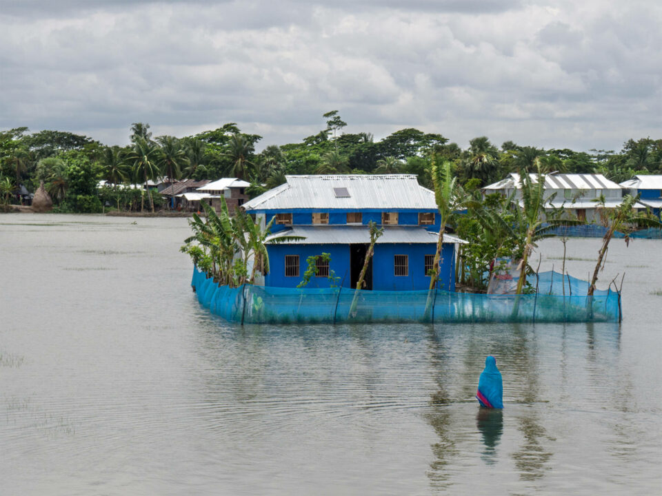 Woman looking at her submerged house in Bangladesh