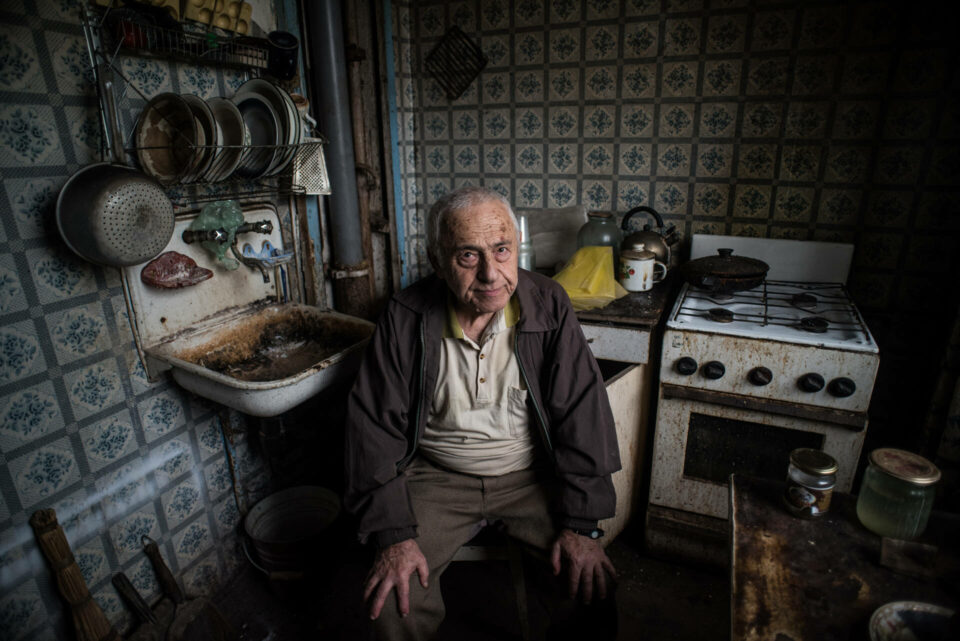 Elderly man sitting in his dilapidated kitchen