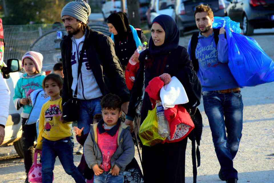 Family of refugees carrying belongings, looking distressed